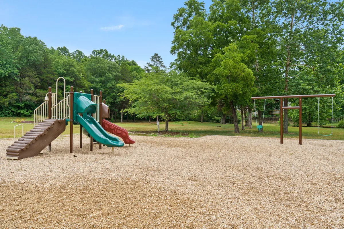 An inviting playground complete with swings and colorful play equipment, set outdoors with ample space for children to play and families to gather. The scene captures the joy of outdoor play and family bonding.