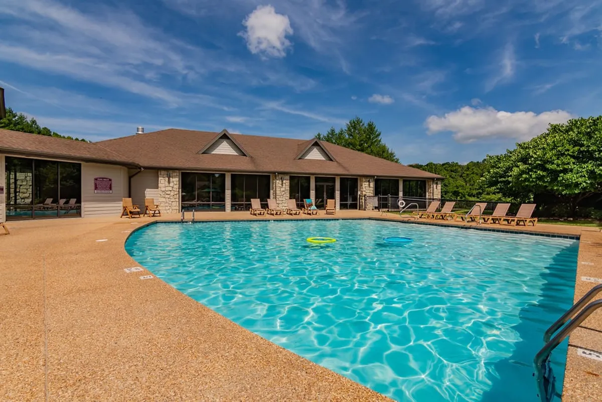 A cheerful exterior view of one of the seasonal saltwater pools framed by lounge chairs and a building with large windows, suggesting an inviting and relaxing environment for families and friends to gather, swim, and unwind.