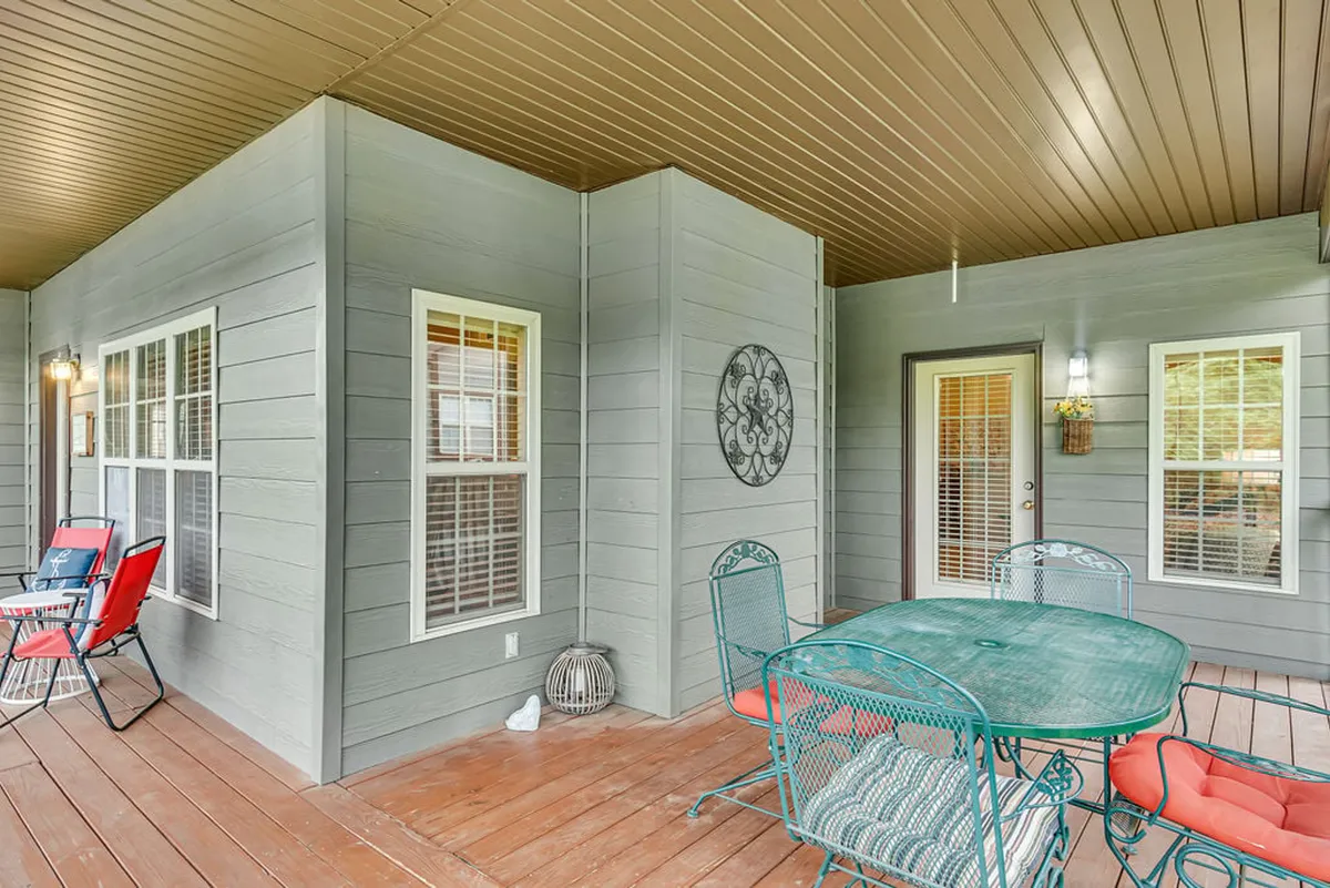 An inviting outdoor patio setting with a metal table and chairs, a bright red folding chair, and decorative wall art. The patio space overlooks lush greenery, providing a comfortable spot to enjoy morning coffee, watch wildlife, or relax as the sun sets.