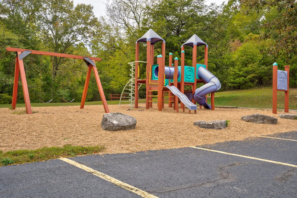 A joyful exterior image of a vibrant playground structure featuring swings and climbing frames, with children and families enjoying the outdoors. It radiates energy and community spirit—the ideal setting for family fun and playdates.
